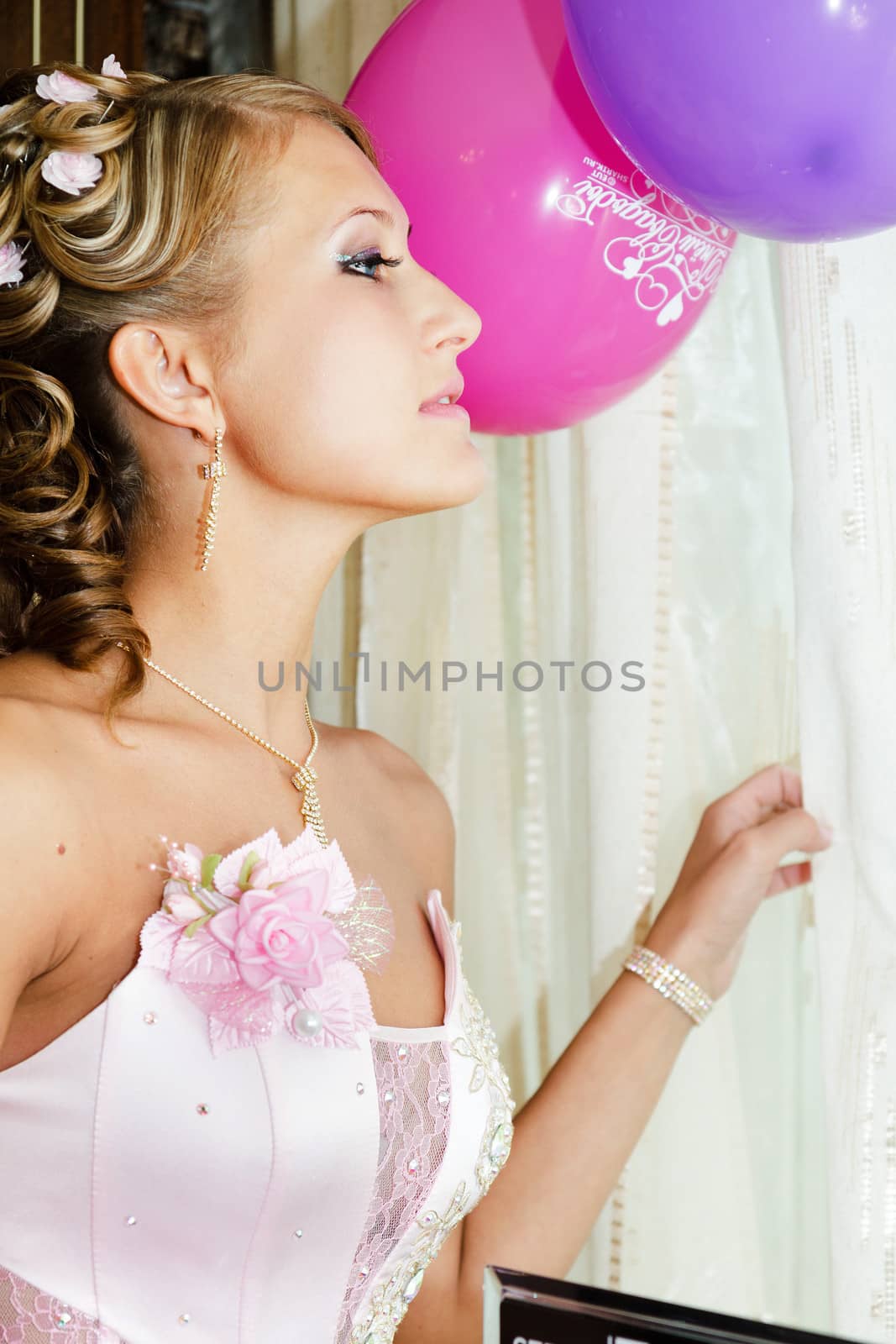 Beautiful bride in a pink dress looking out the window