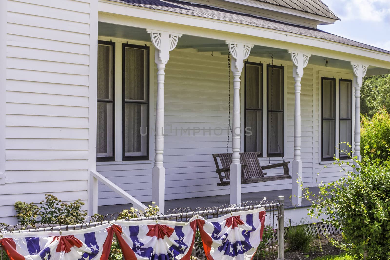 A side view of the front porch of a vintage style wooden home.