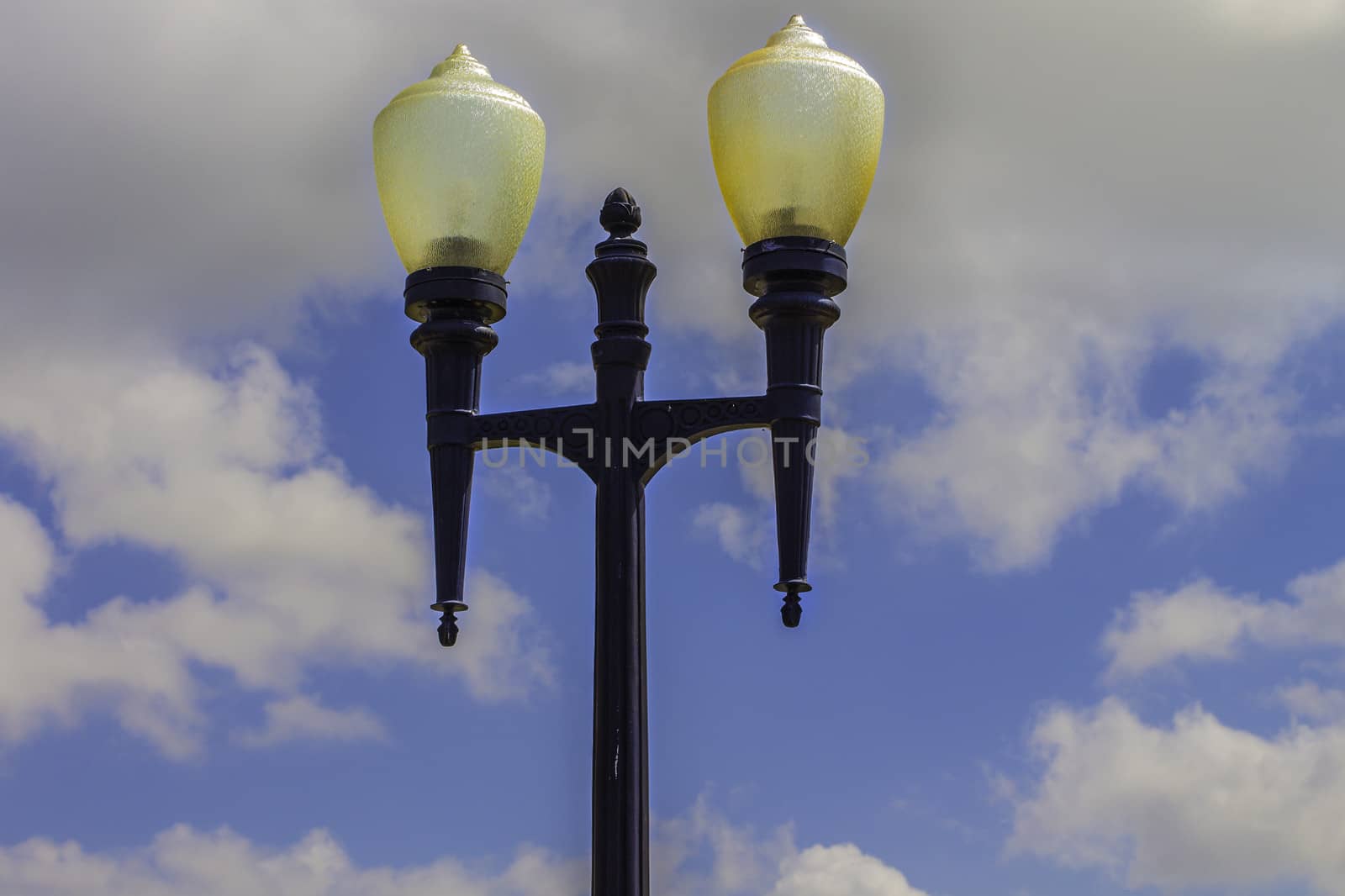 A vintage lamp post in an old park with a blue sky in the background.