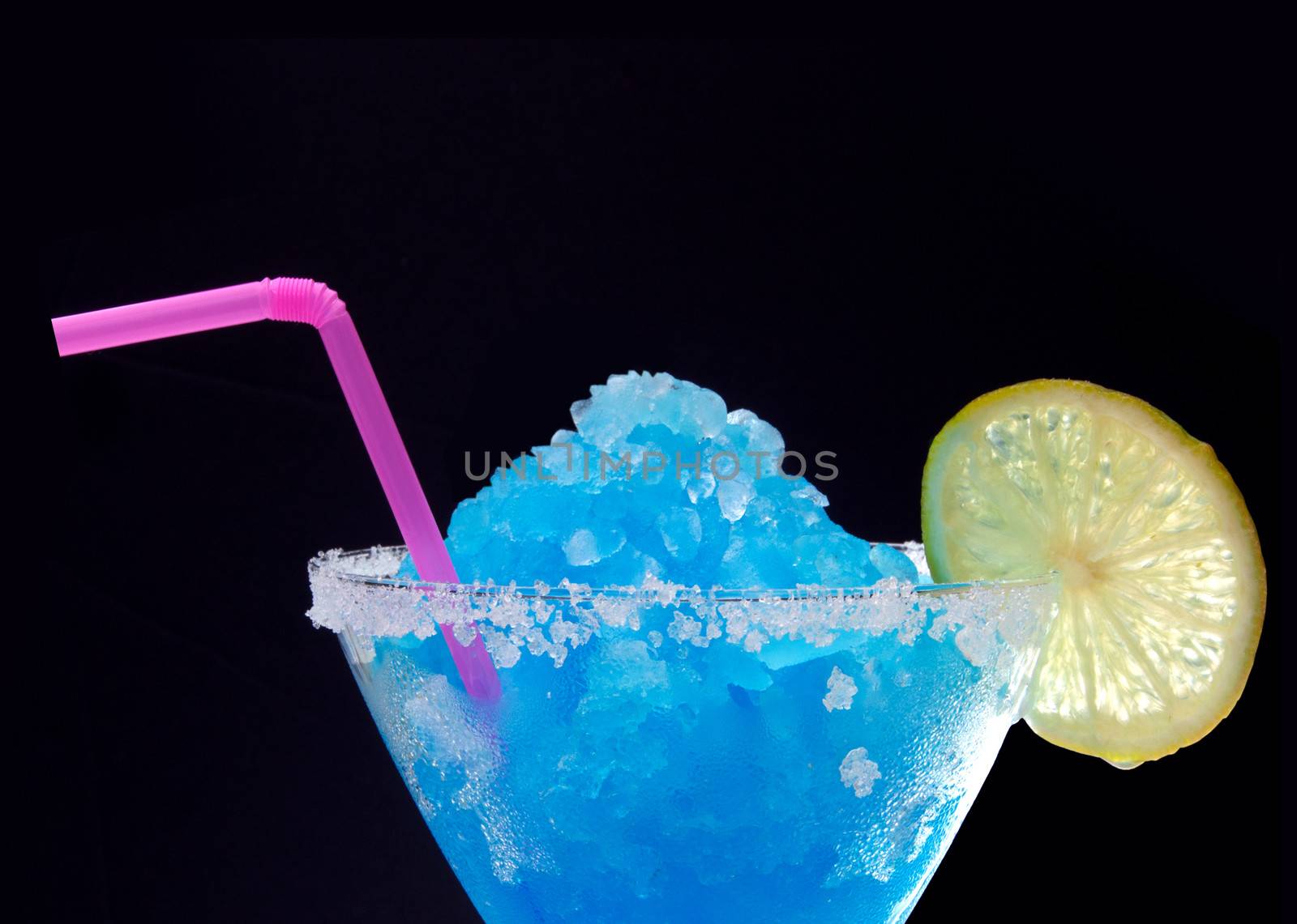 Frozen crushed ice blue cocktail with slice of lime and straw 