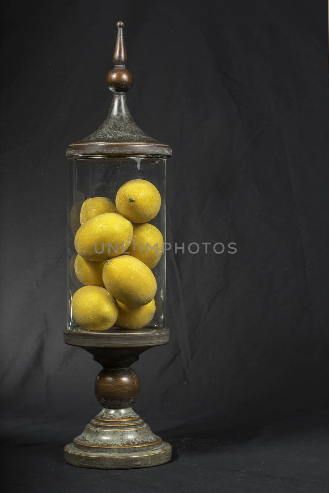A decorative vintage glass jar filled with lemons.