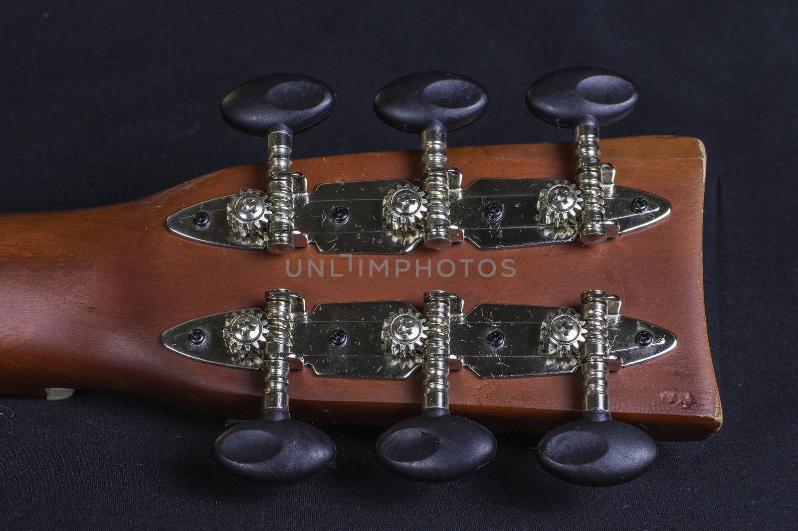 The handle of a classical guitar showing the gears and knobs.