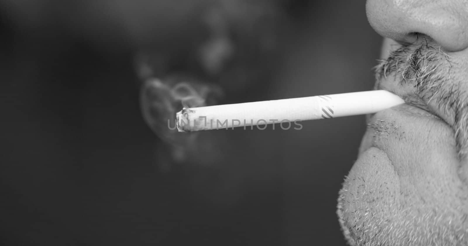 Man smoking a cigarette against a black background (black and white)