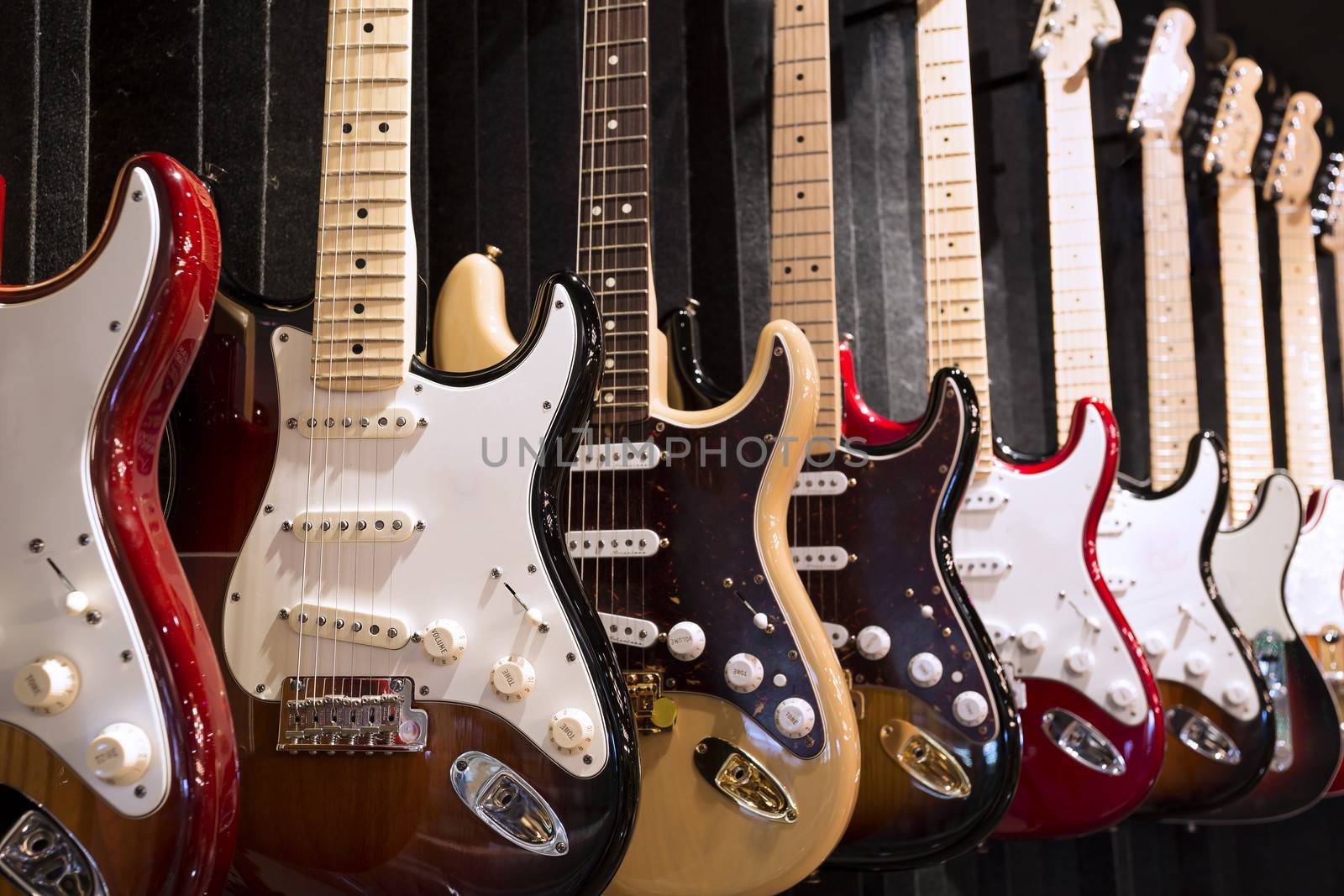 Many electric guitars hanging on wall in the music instrument shop 