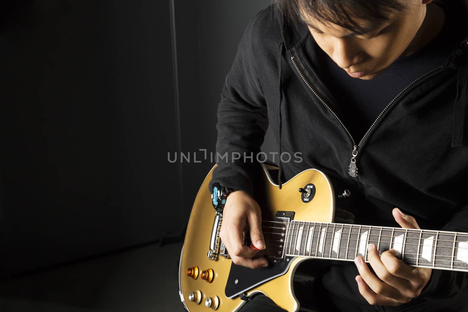 An Asian guitarist playing electric guitar with copy space on the left.