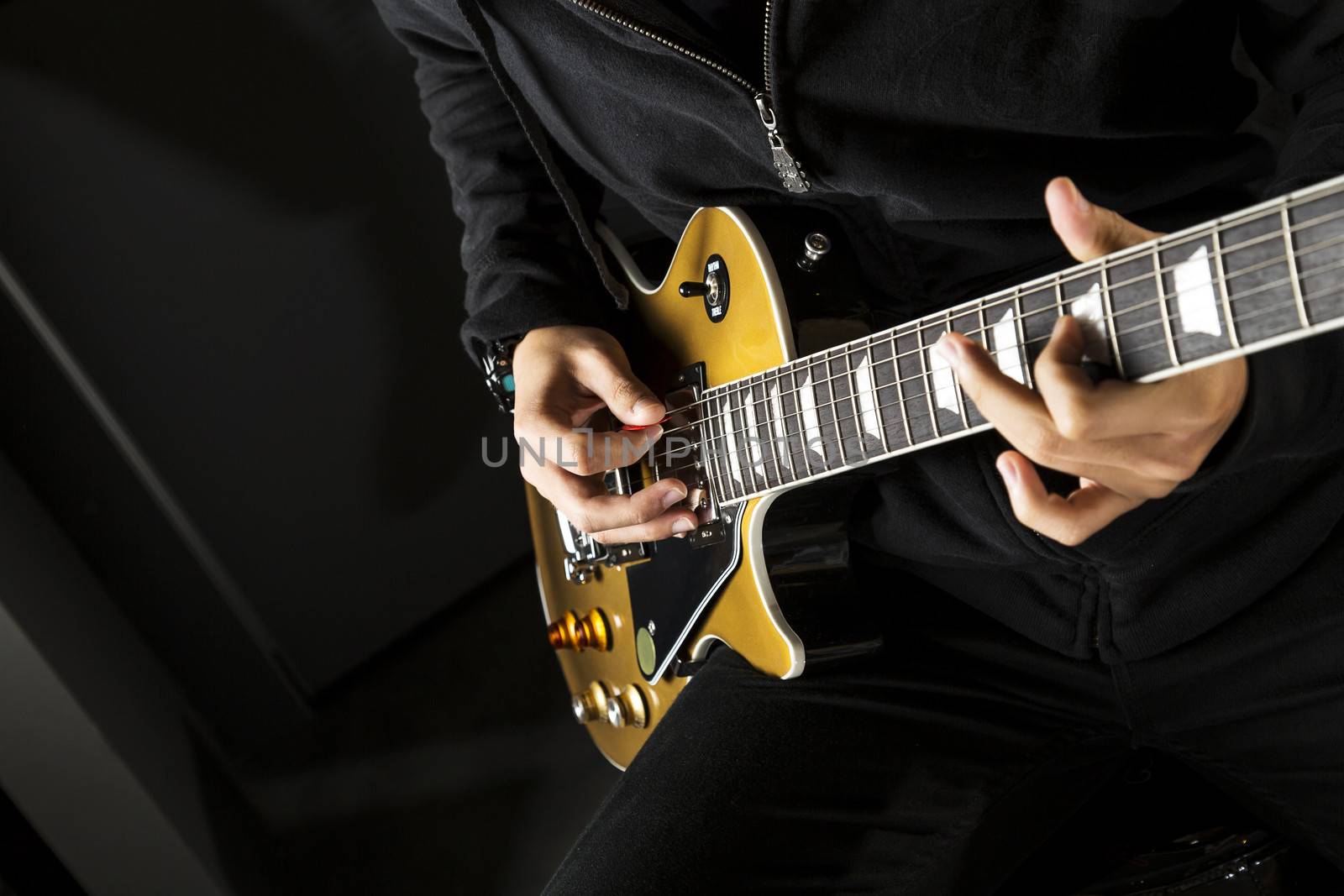 Close up of a boy playing a electric guitar.