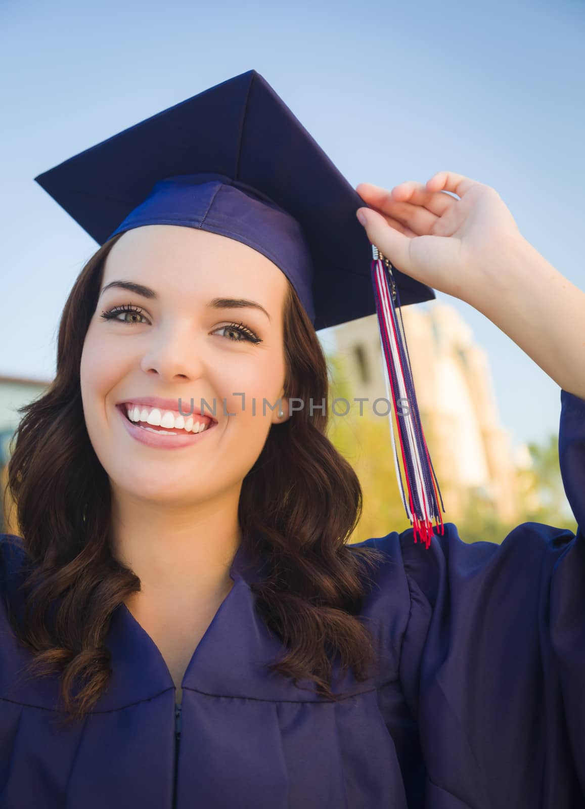 Happy Graduating Mixed Race Woman In Cap and Gown Celebrating on Campus.