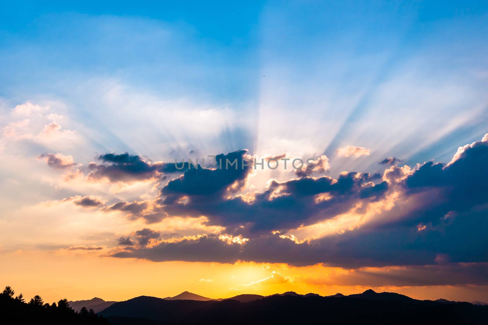 Sunset / sunrise with clouds, light rays and other atmospheric effect over the hills and mountains in Slovenia, Europe.