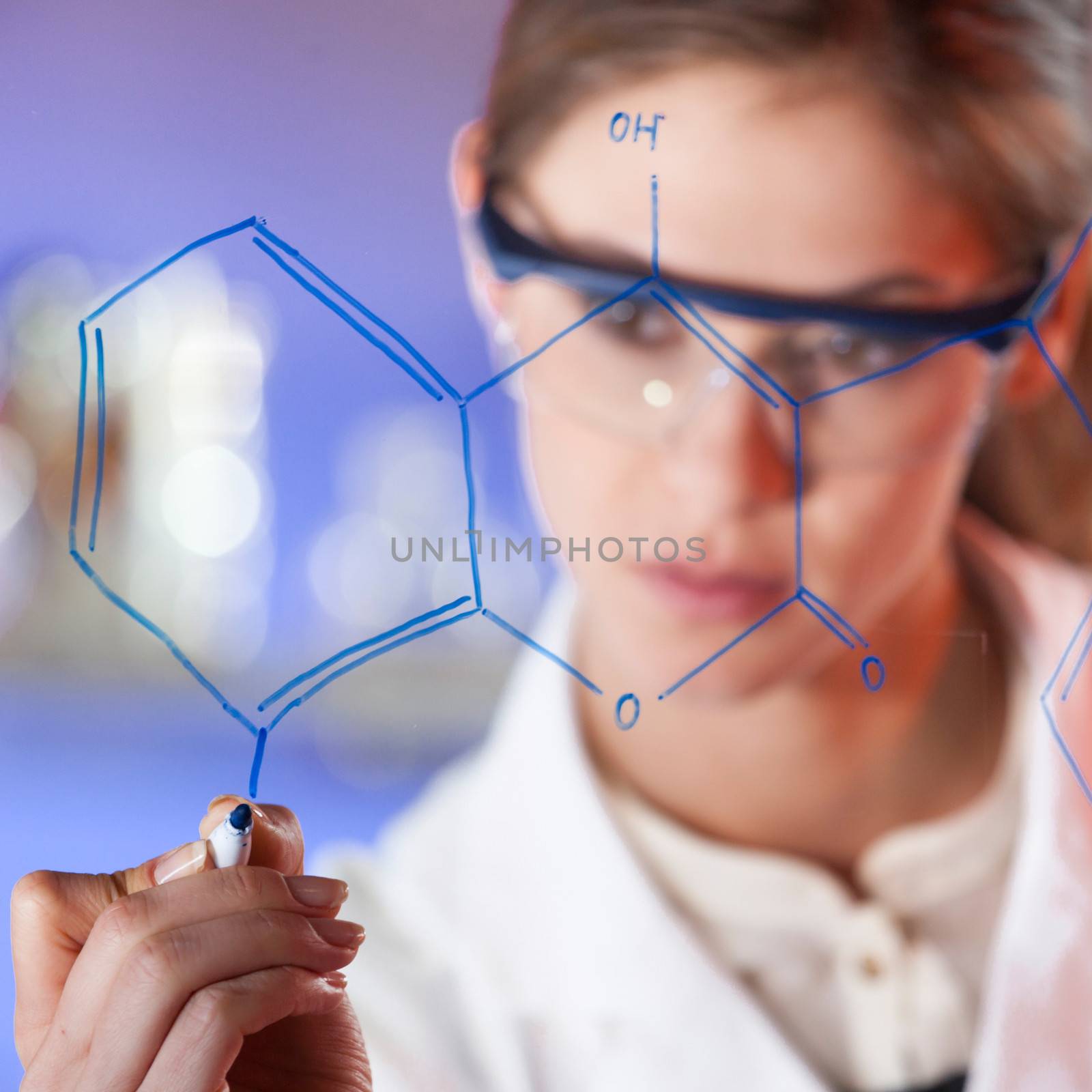 Portrait of a confident female health care professional in his working environment writing structural chemical formula on a glass board.
