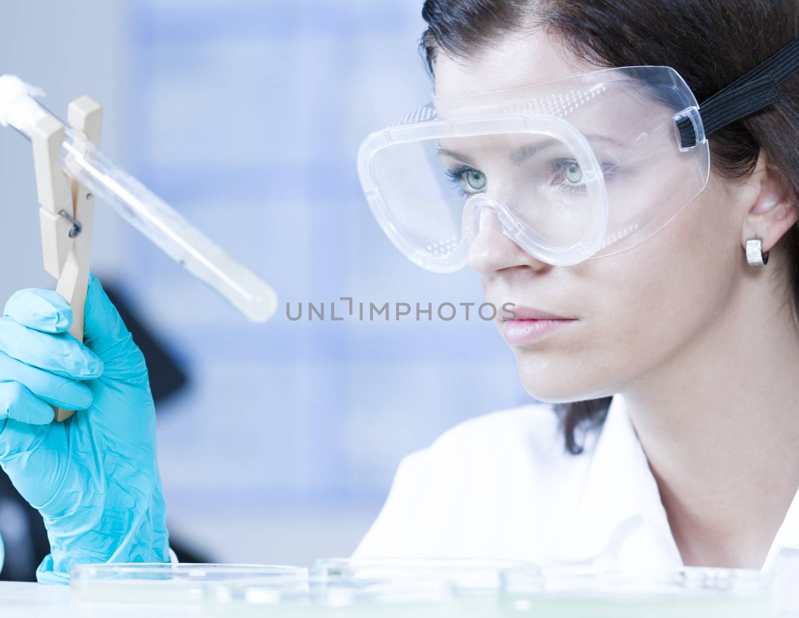 Attractive young female scientist observing bacterial colonies in the glass tube in the life science research laboratory (biochemistry, genetics, forensics, microbiology..)