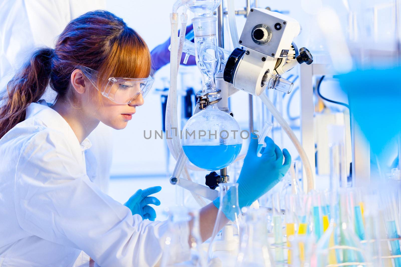 Chemical laboratory scene: attractive young PhD student scientist observing the blue indicator color shift after the solution  destillation.