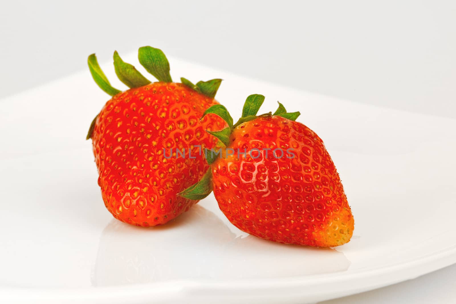 Two berries of strawberry on a white plate