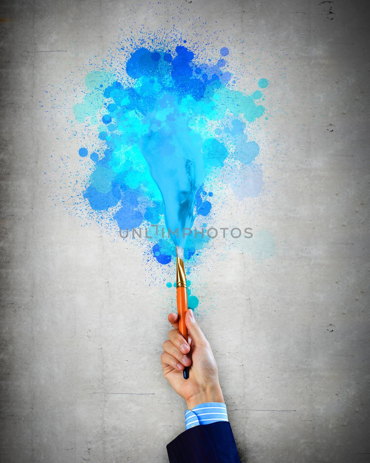 Close-up of human hand holding paint brush making colorful paint splashes