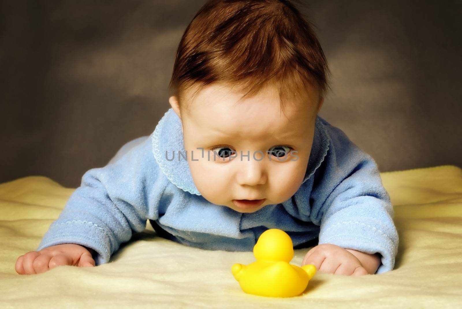 A child with surprise considers a toy duck.
