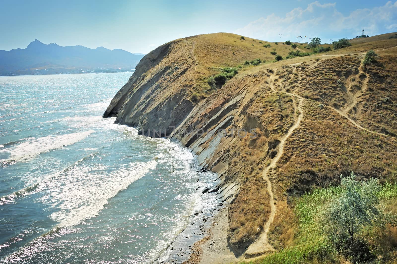 Steep cliff at the edge of the sea, against the backdrop of the Crimean Mountains.