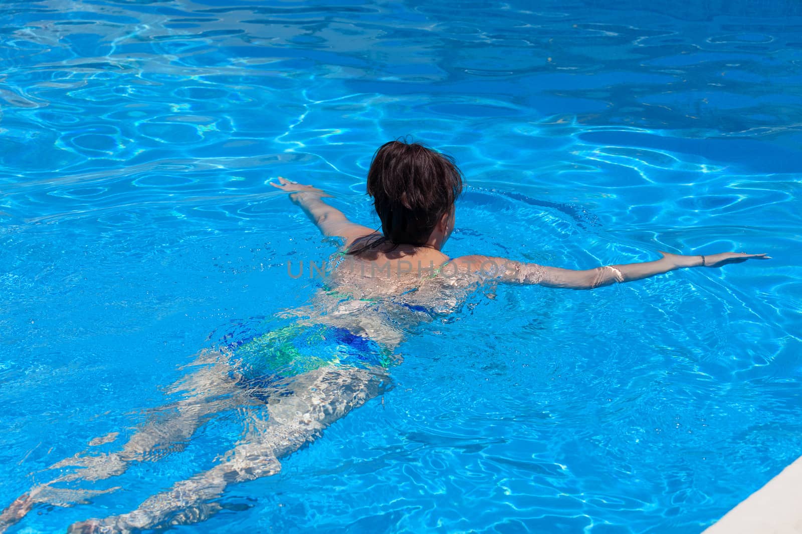 Middle-aged woman swims in the swimming pool by Discovod