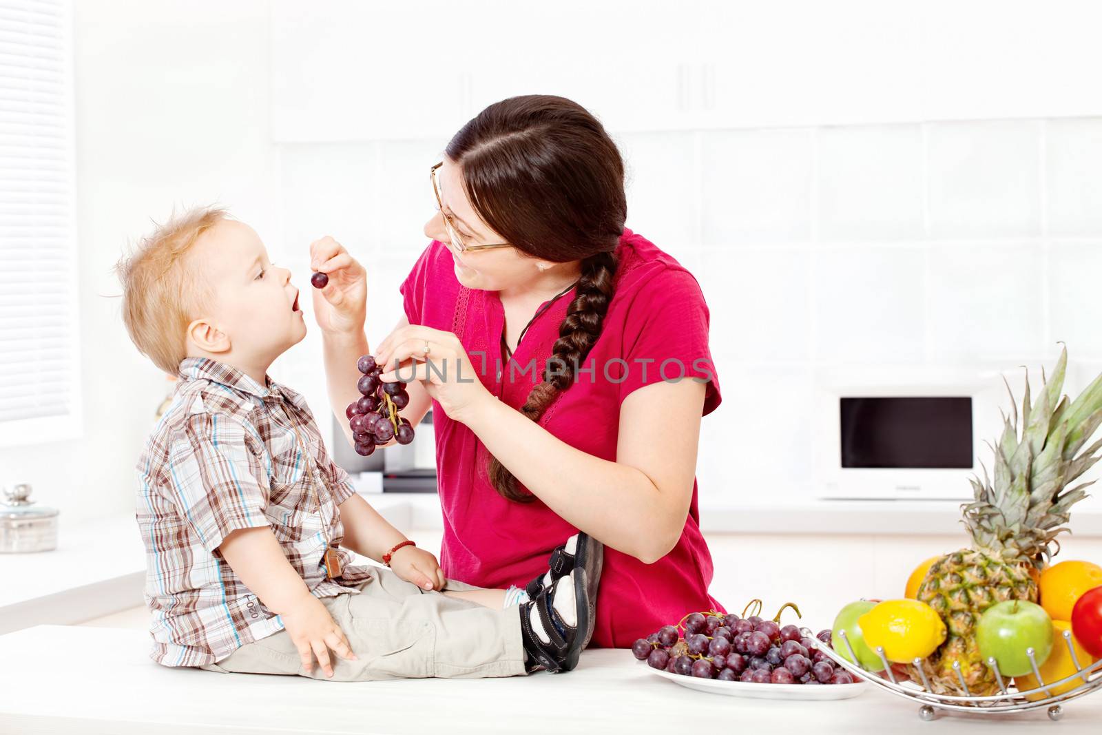 Mother feeding child with grapes by imarin
