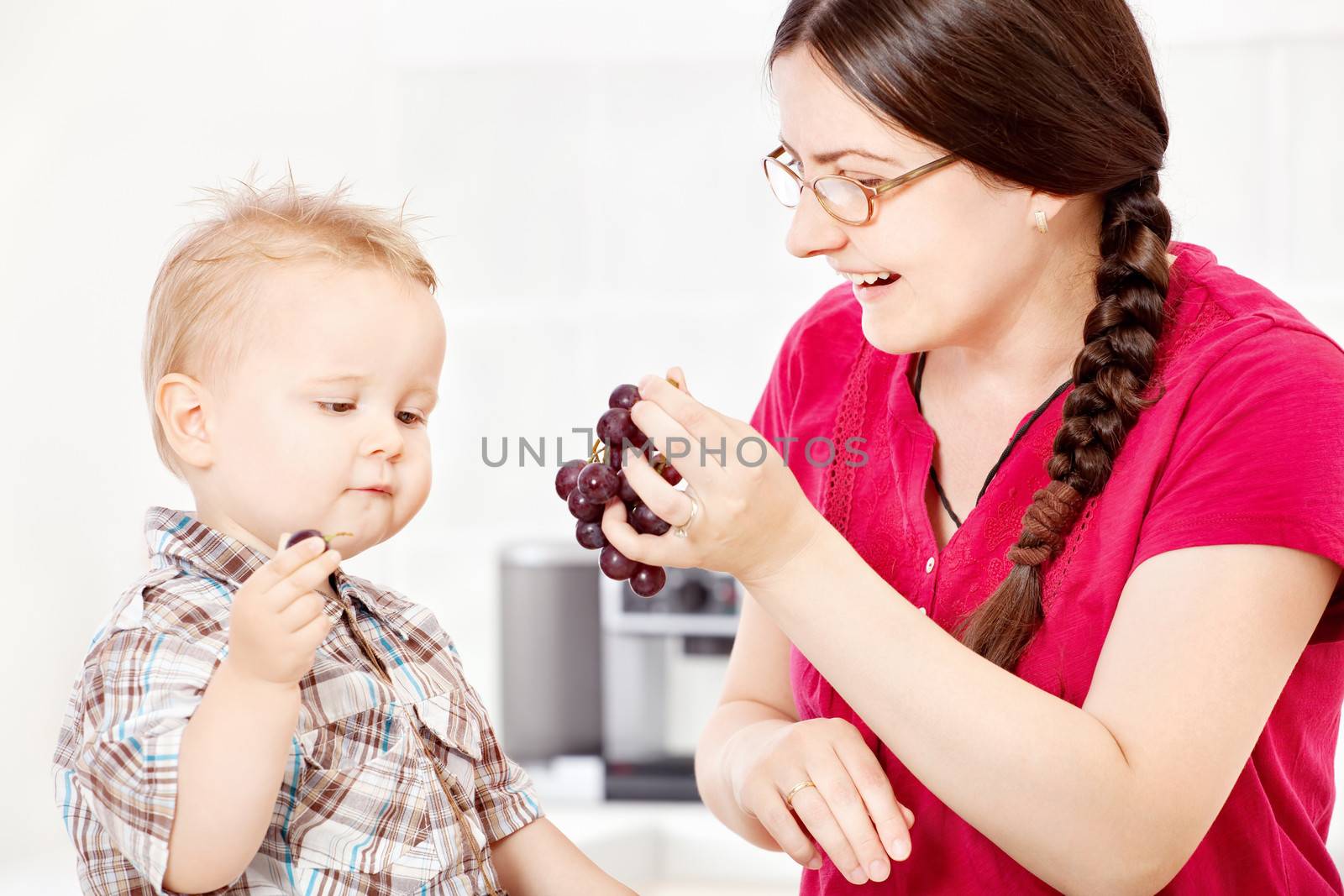 Mother feeding child with grape by imarin