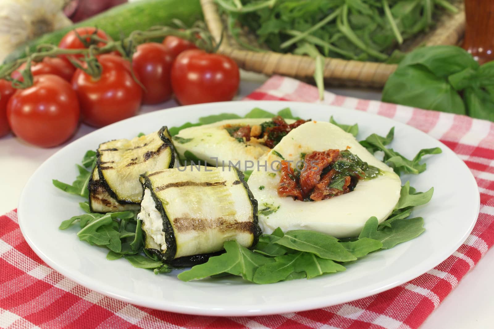 Courgette rolls filled mozzarella and rocket salad on a bed