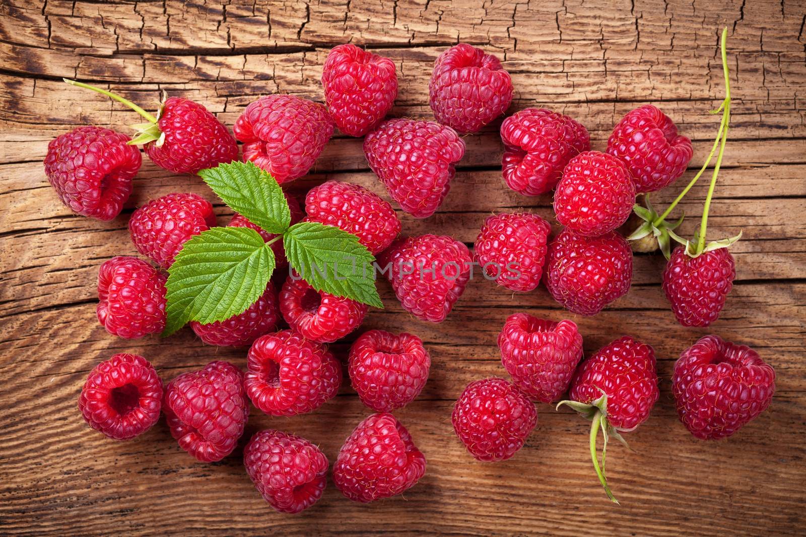 Raspberries with leaf on wooden table background. Top view