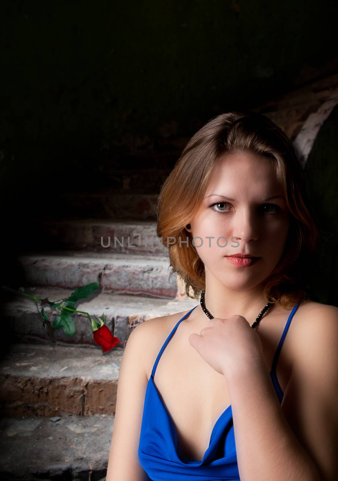 young woman near abandoned staircase with red rose