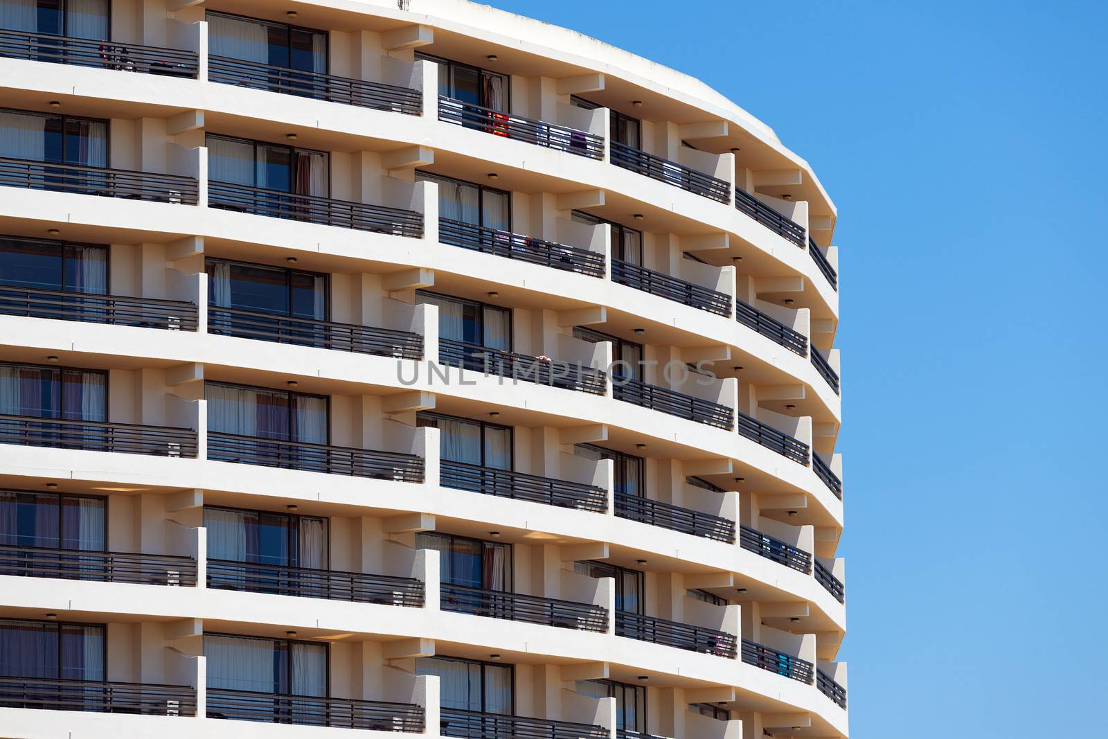 Exterior of a modern apartment block or hotel with a curved rounded design against a blue sky