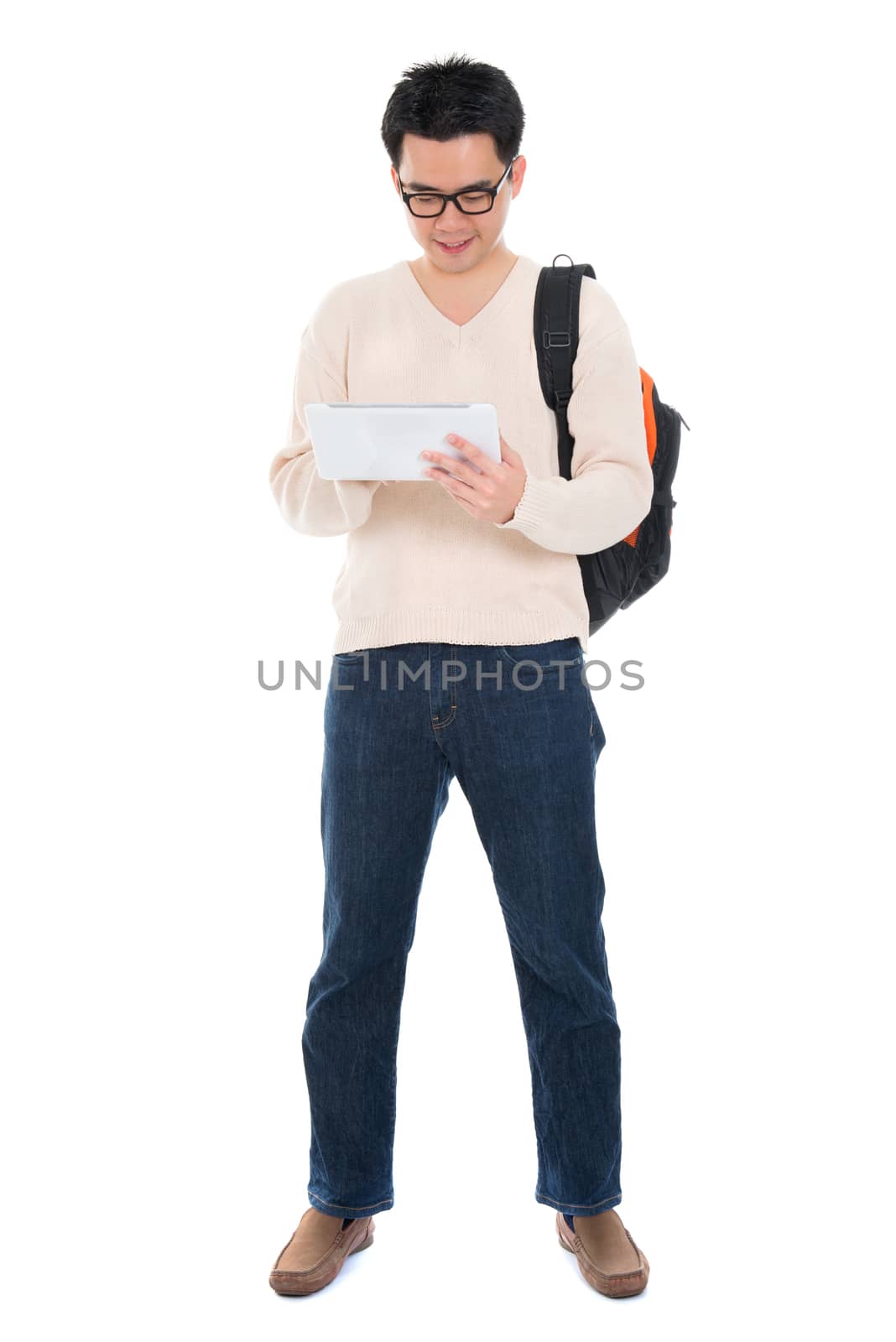Full body Asian adult student in casual wear with school bag using digital computer tablet pc standing isolated on white background. Asian male model.
