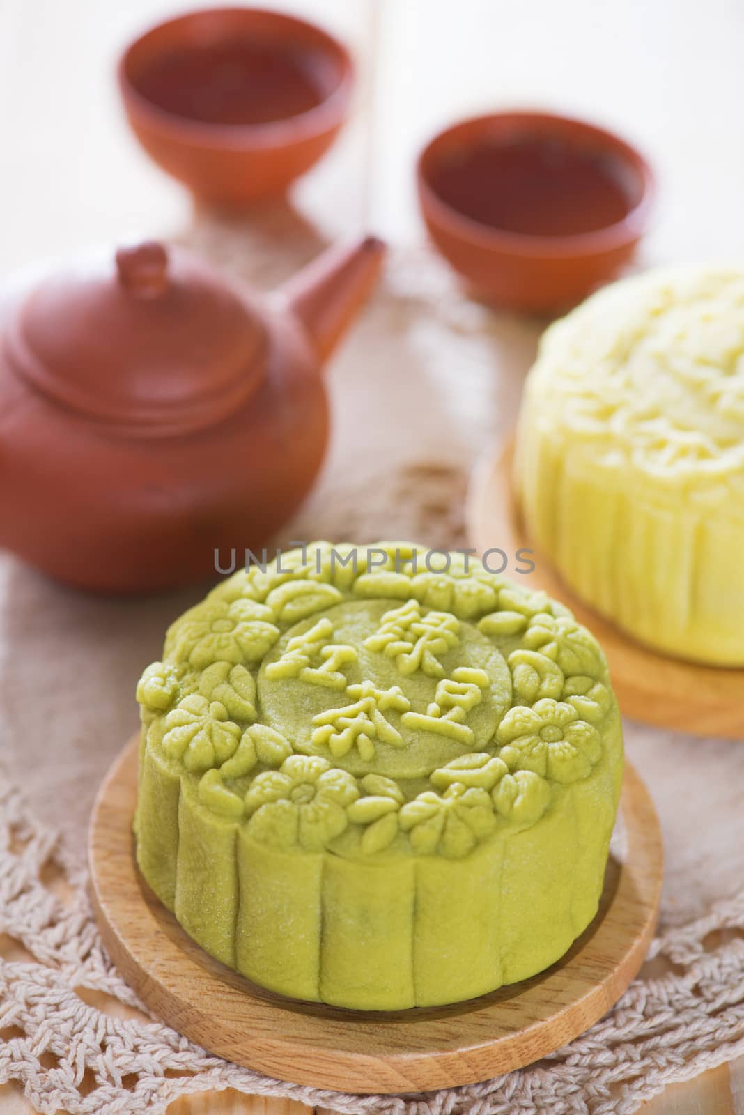Snowy skin mooncakes.  Traditional Chinese mid autumn festival food and tea set. The Chinese words on the mooncakes means green tea with red bean paste and lotus paste, not a logo or trademark.
