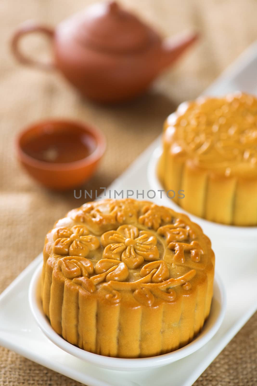 Chinese mid autumn festival foods. Traditional mooncakes on table setting with teapot.  The Chinese words on the mooncakes means assorted fruits nuts, not a logo or trademark.