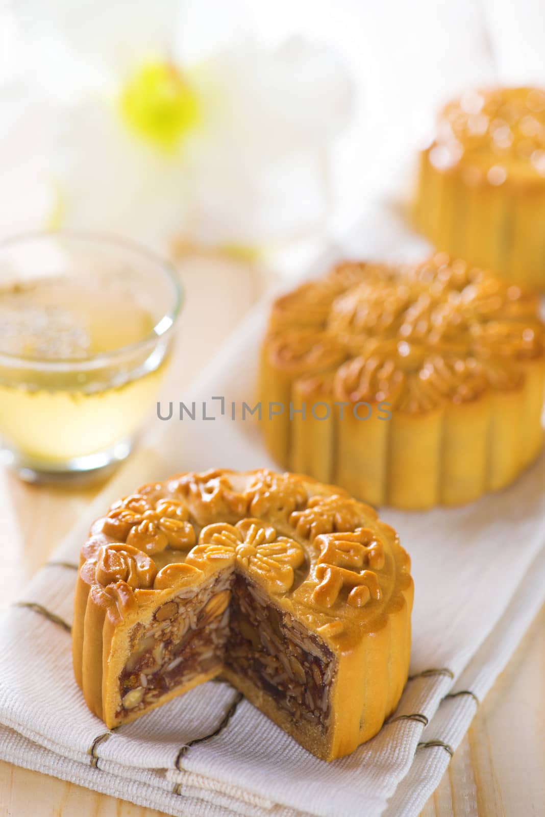 Chinese mid autumn festival foods. Traditional mooncakes on table setting with teacup.  The Chinese words on the mooncakes means assorted fruits nuts, not a logo or trademark.