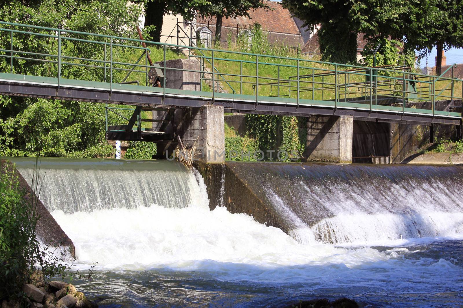 a dam retaining water from a swollen river with its bridge and waterfall