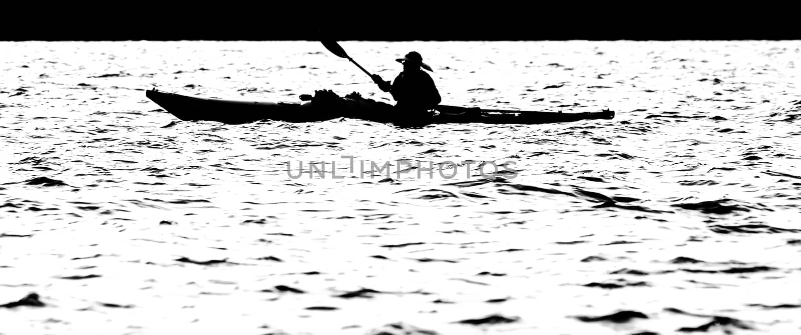 Sillouette of man kayaking on lake in the morning