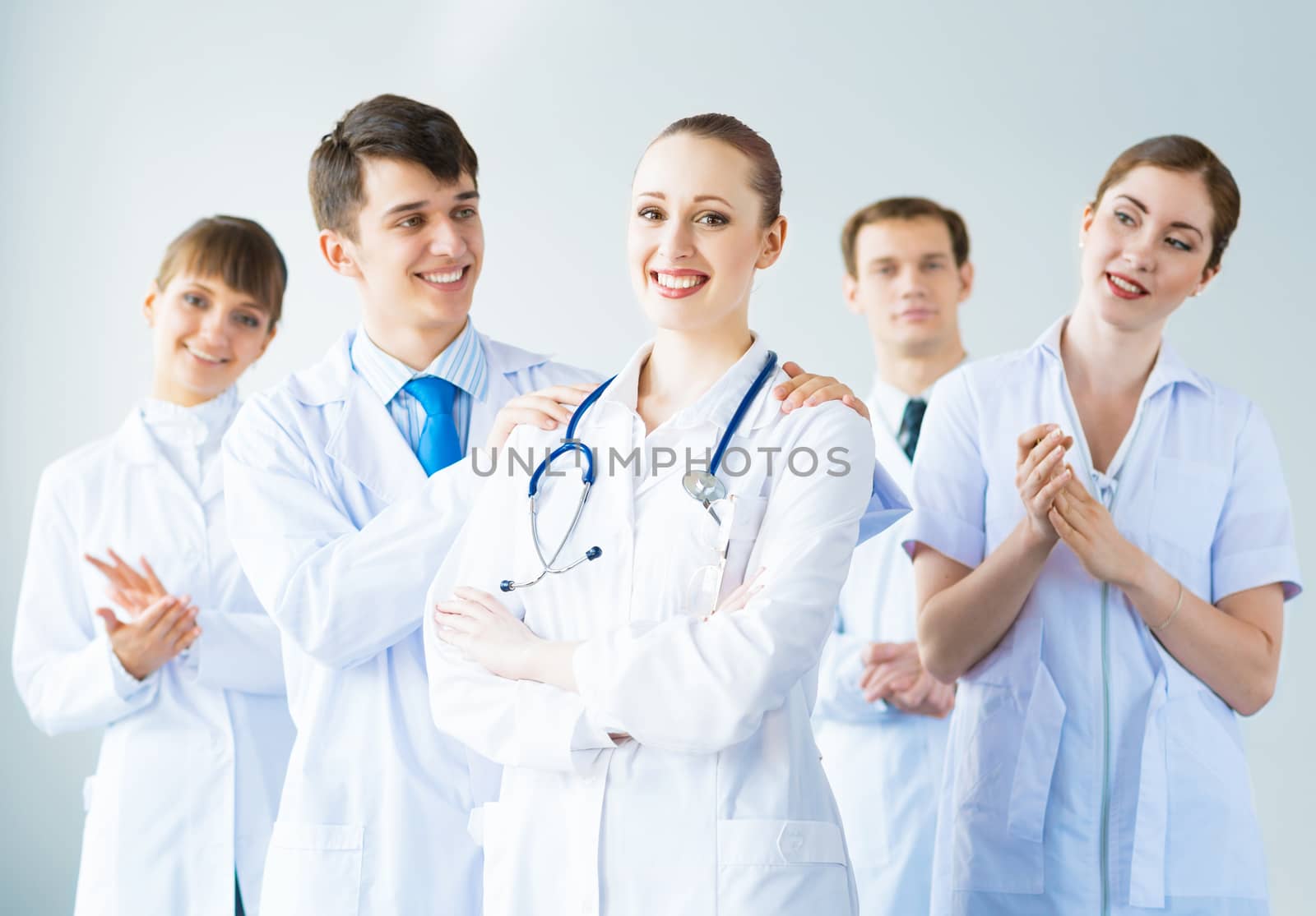 successful doctor, accepts congratulations from colleagues, stand behind him and clap