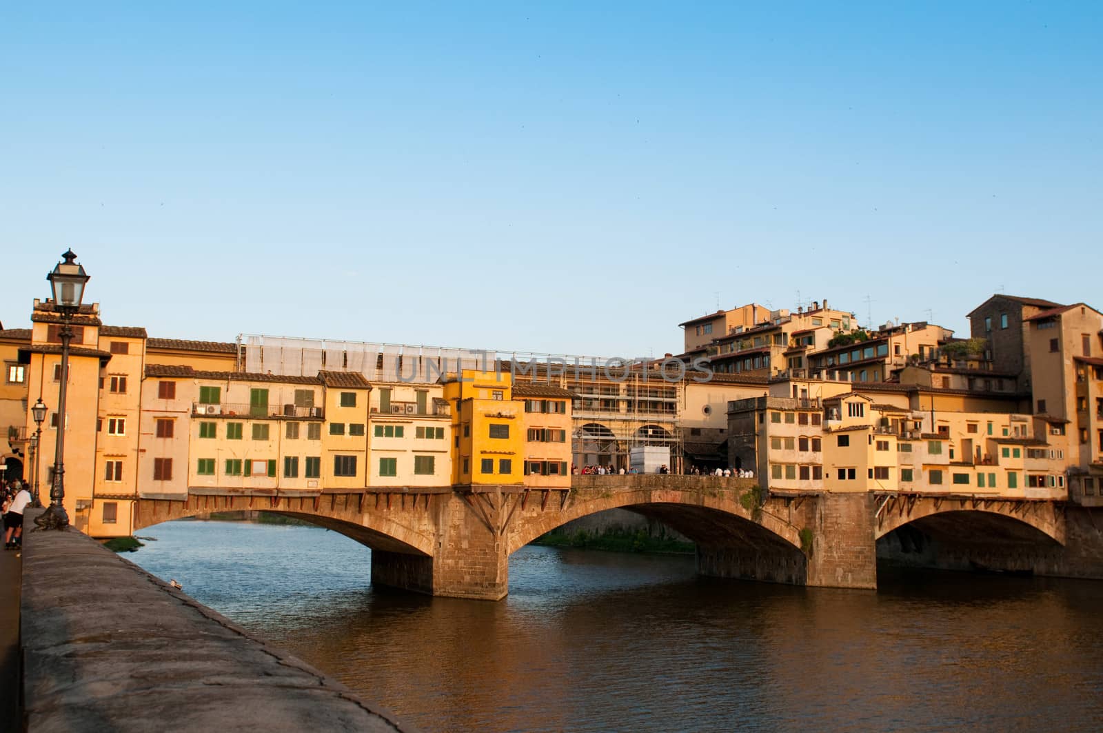 Crowds of tourists visit the Ponte Vecchio ("Old Bridge") which is a Medieval bridge over the Arno River at evening.  Florence, Tuscany, Italy.