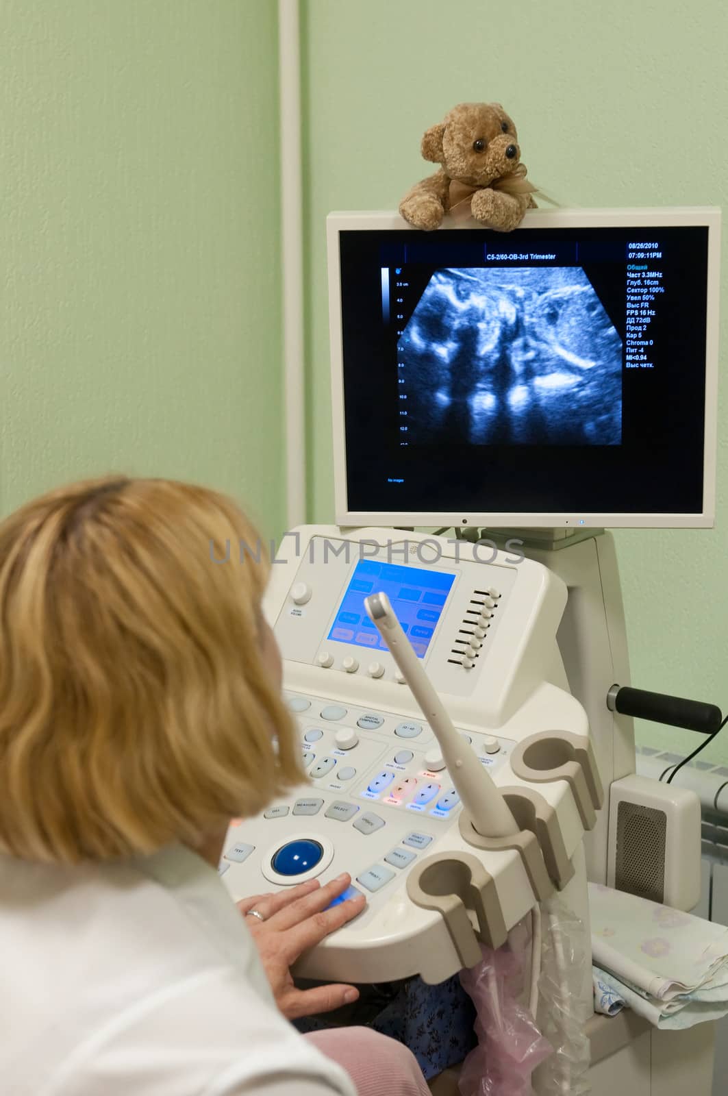 Obstetrician examining pregnant belly by ultrasonic scan.