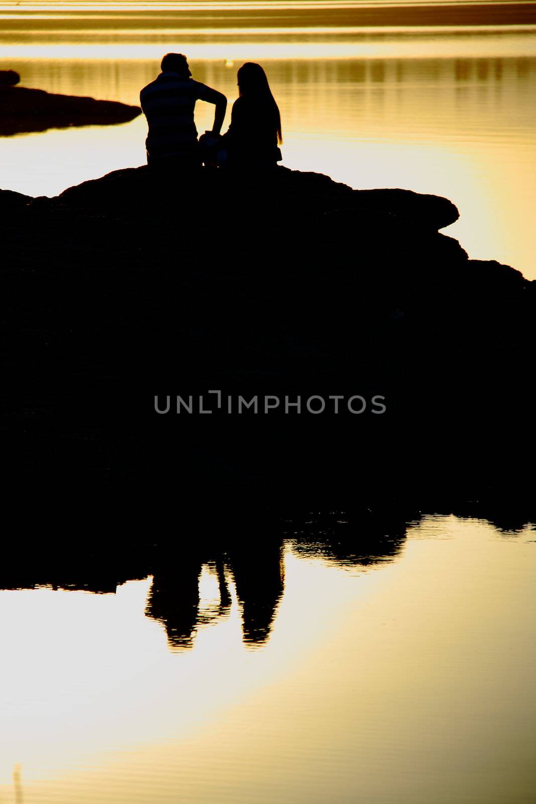 romantic couple watching sunset while sitting