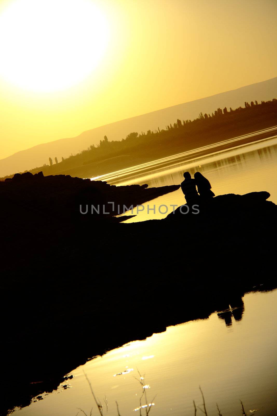 romantic couple watching sunset while sitting