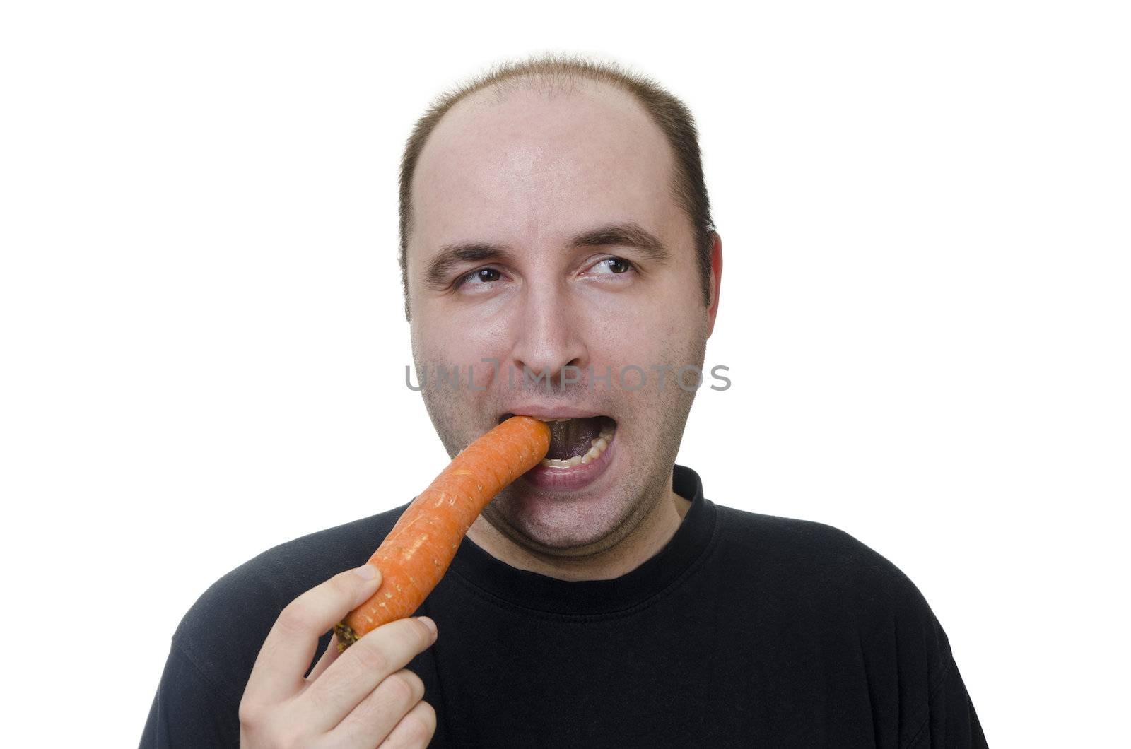 young man making a sour face eating a carrot on white background