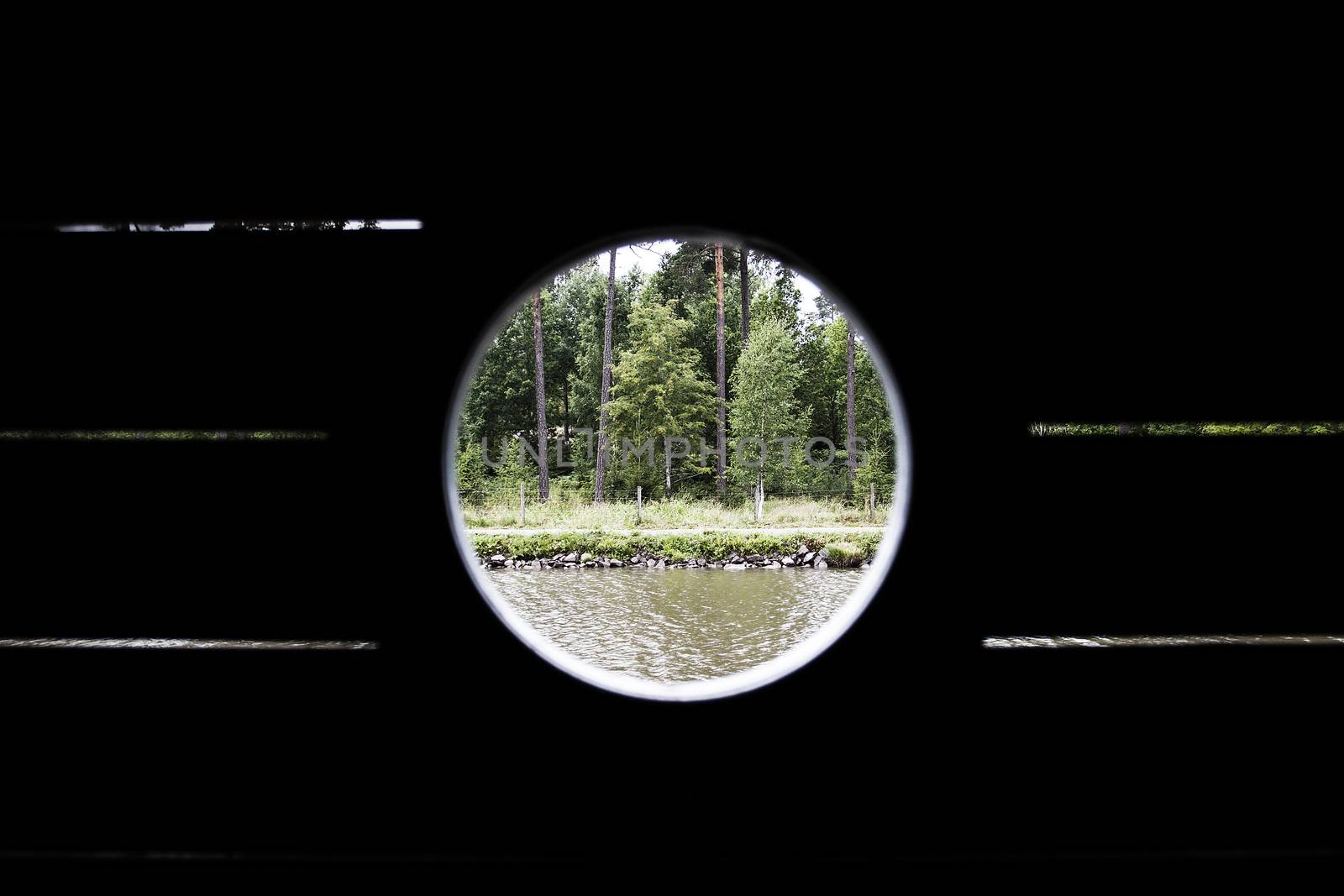 View from inside a boat through a porthole over Gota Kanal Sweden