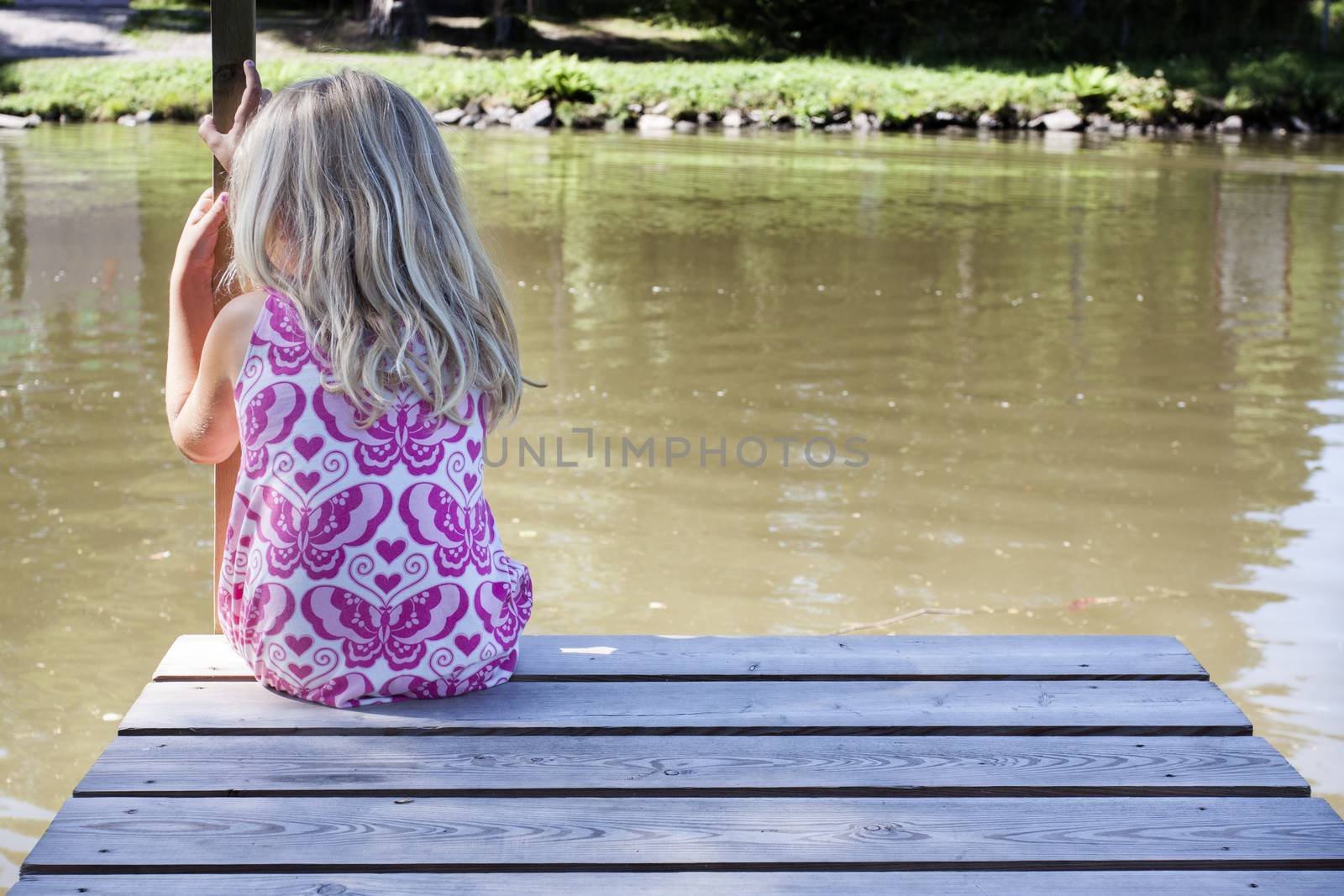 A little child sitting along on the river bank