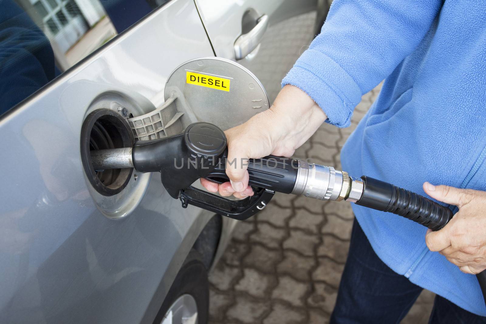 A hand filling up a car with diesel