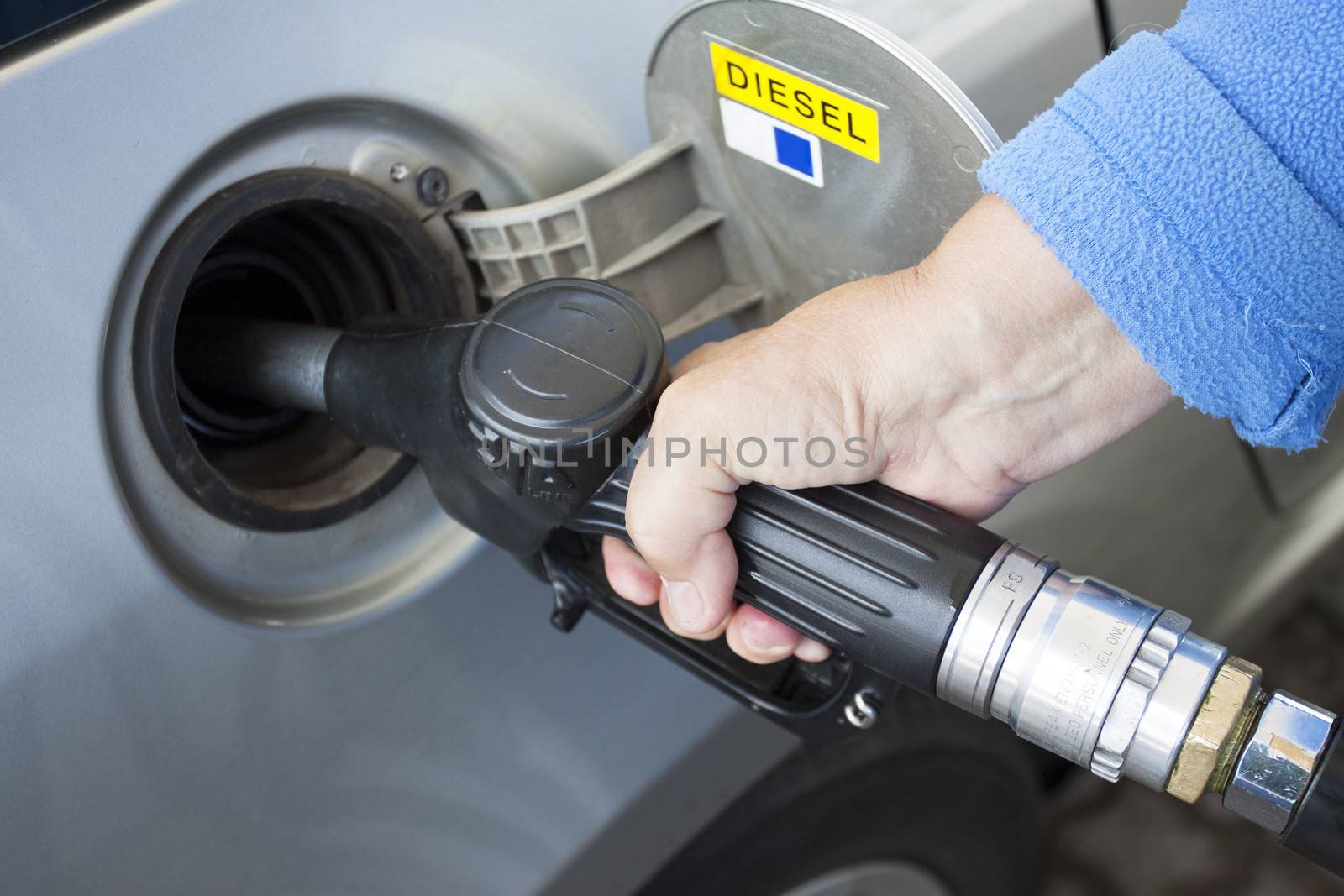 A hand filling up a car with diesel