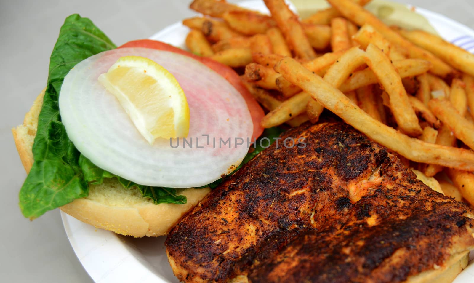 blackened fish sandwich with lettuce, tomato and onion