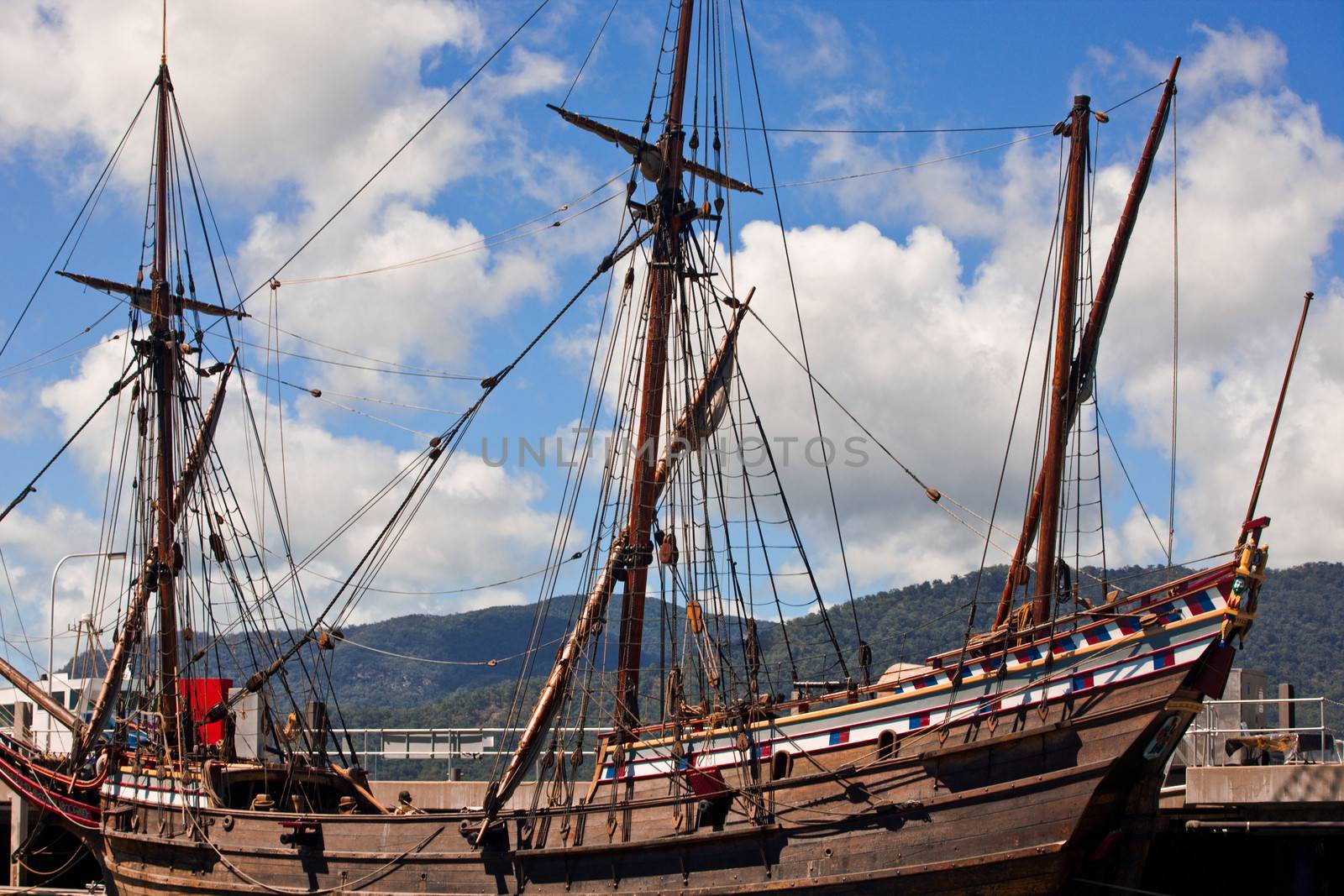 Three masted wooden schooner docked at a quay in harbour with its sails stowed away