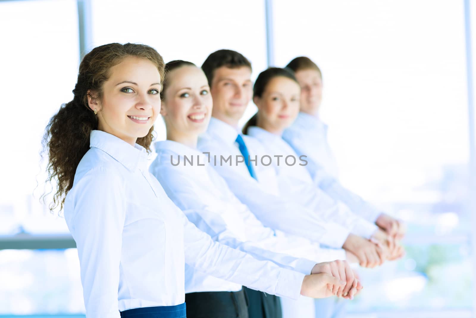 young business people holding hands, standing in a row, the concept of teamwork