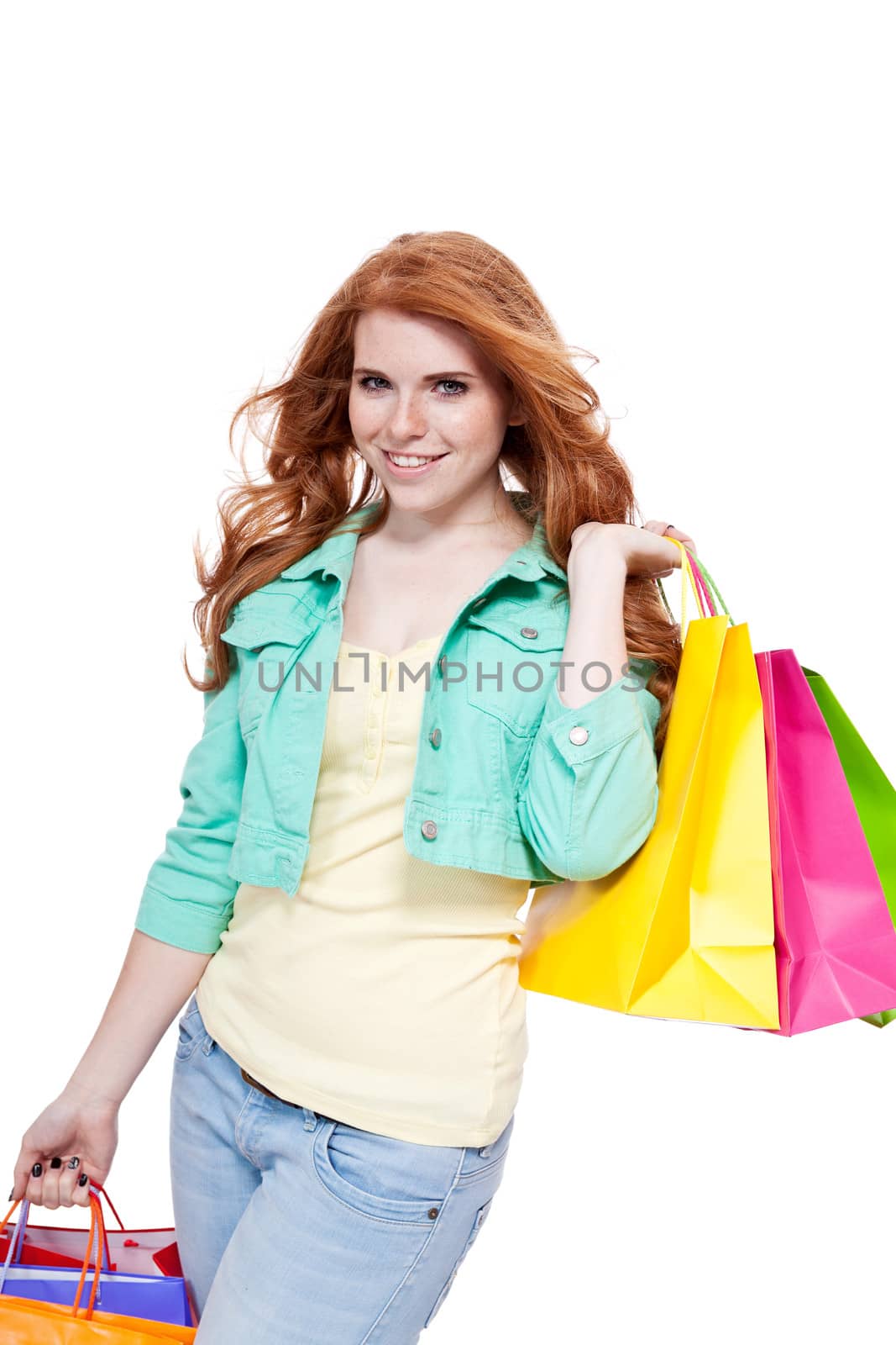 smiling young redhead girl with colorful shoppingbags  isolated on white background