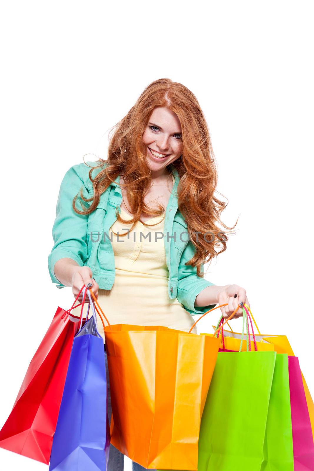 smiling young redhead girl with colorful shoppingbags  isolated on white background