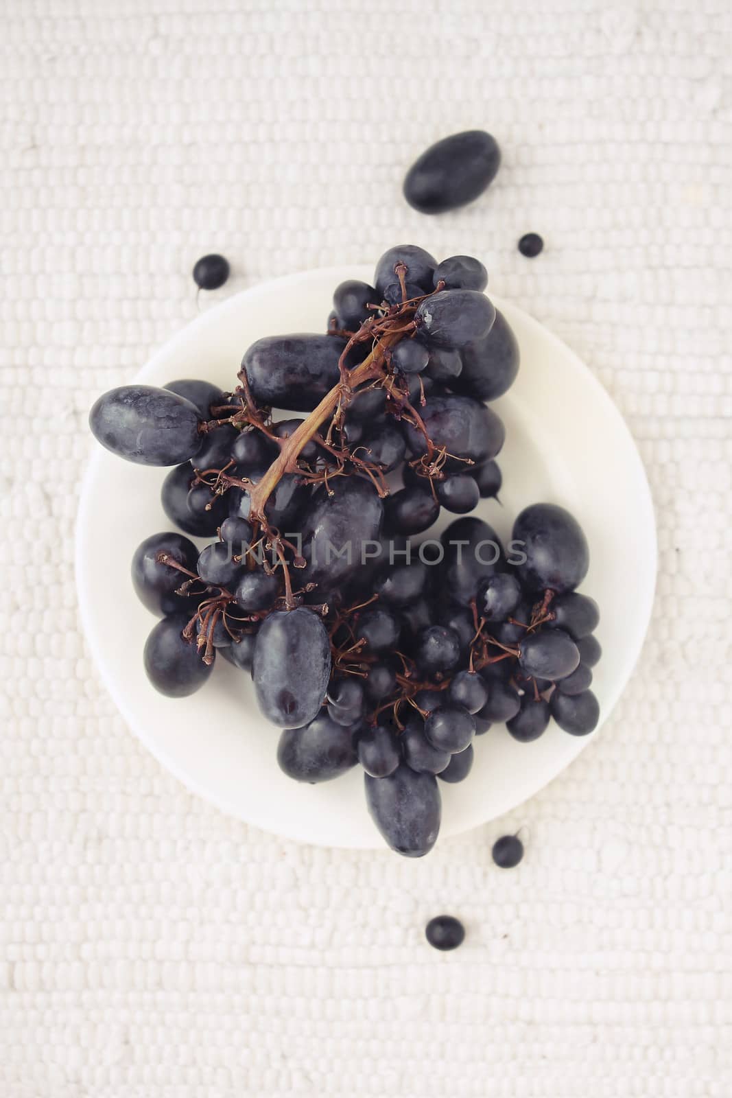 Black grapes on a white plate top view