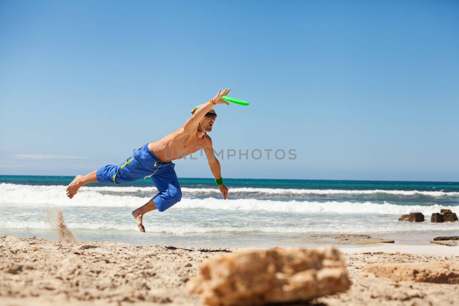 attractive man playing frisby on beach in summer sport fitness jump