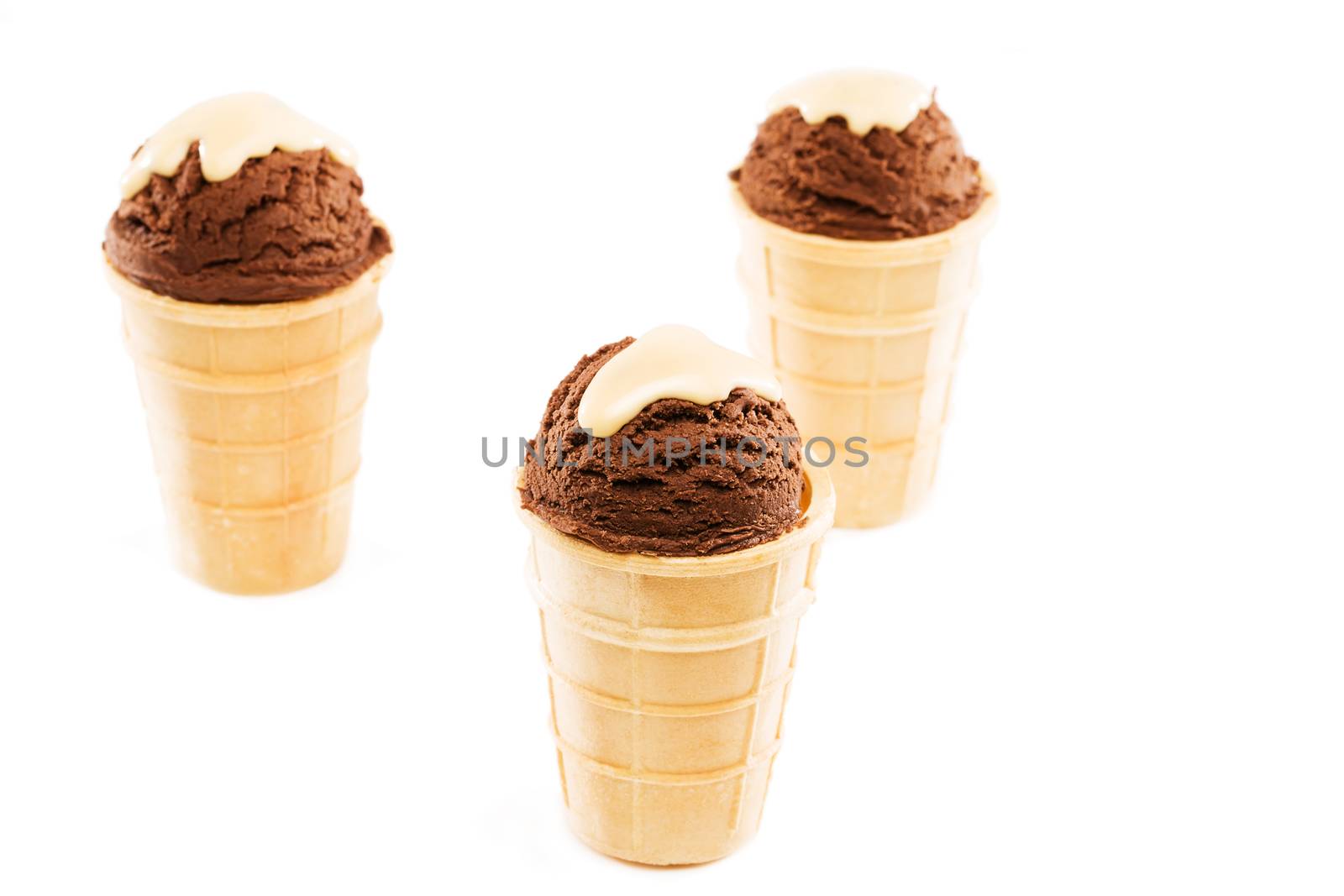 three chocolate ice cream scoops in waffles from top on white background